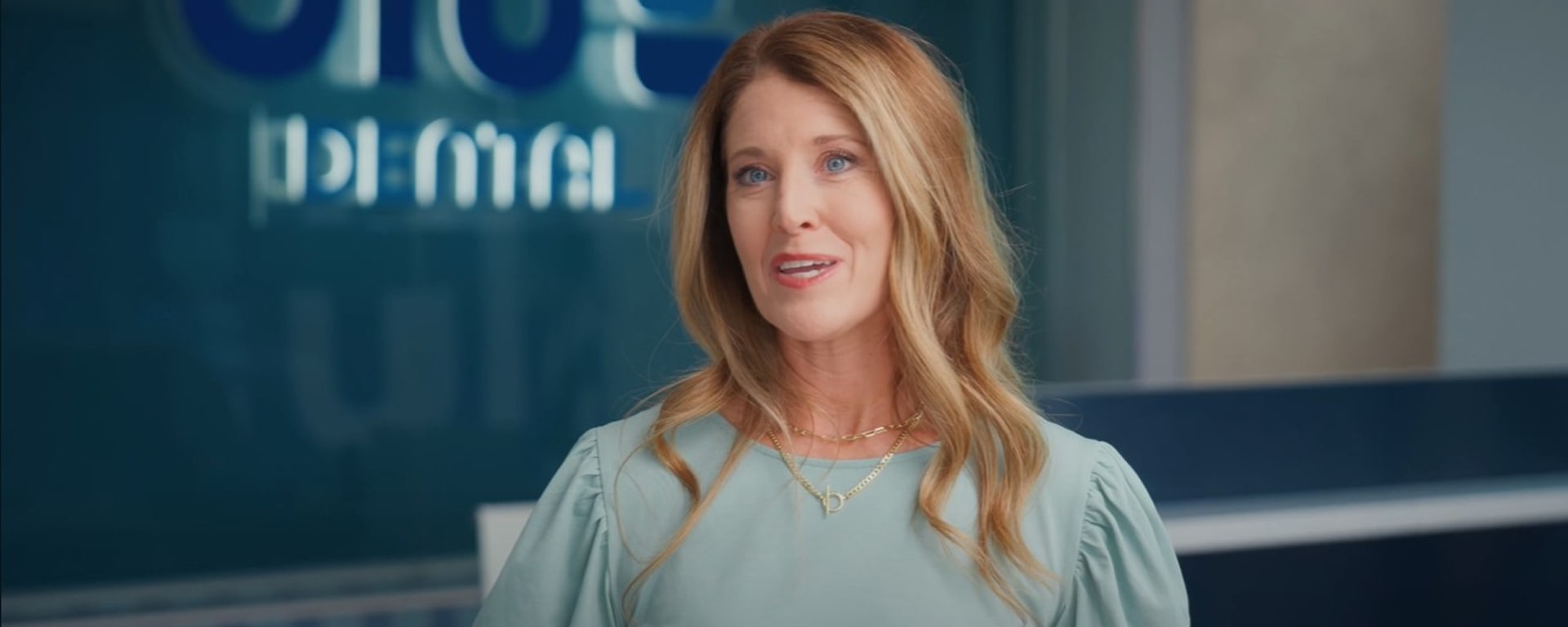 A woman is smiling at Blu Dental while giving her five star testimonial