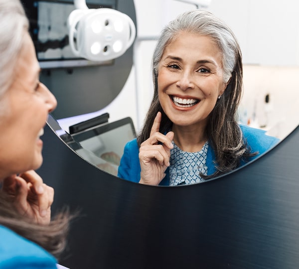 Get the Right Treatment—Only When It’s Needed. A woman is smiling to her reflection in the mirror