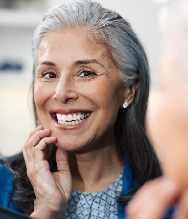 Replace Missing Teeth Easily with Personalized Denture Solutions. A woman is smiling with her new dentures