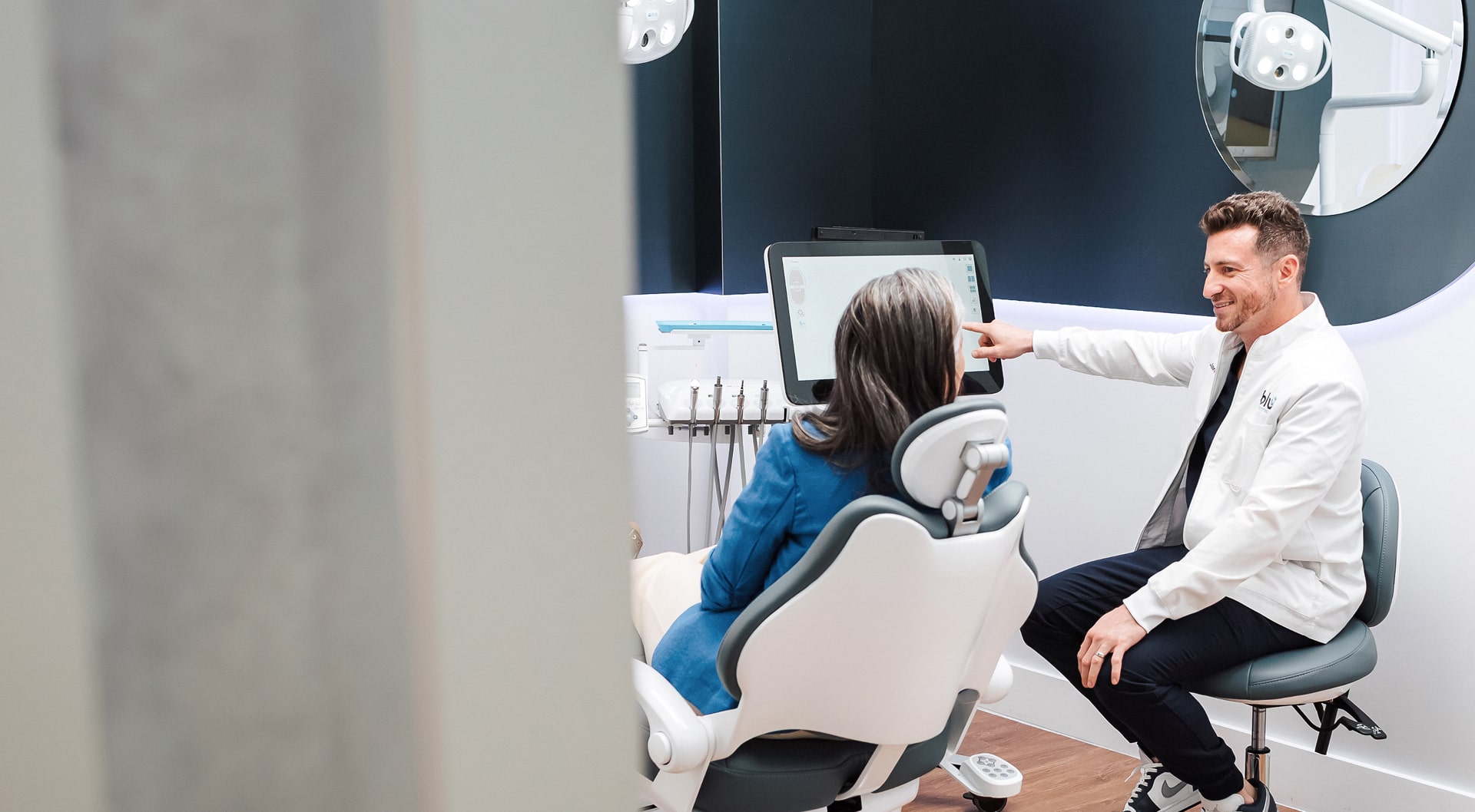 Blu dental dentist is smiling and discussing dentures with a happy patient in a dental chair