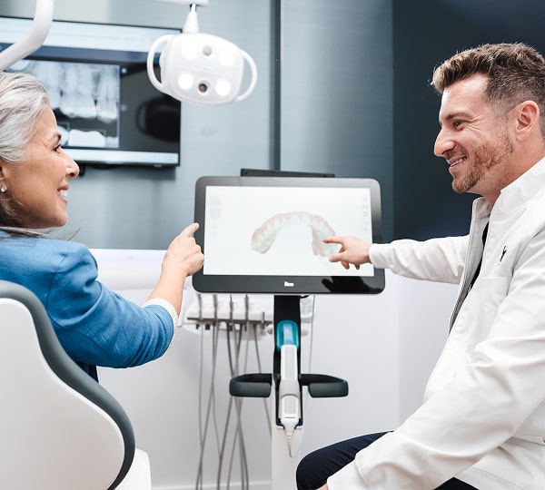 Regain Confidence with Advanced Dental Implants in Miami Shores. Dentist is smiling with a happy patient in a dental chair