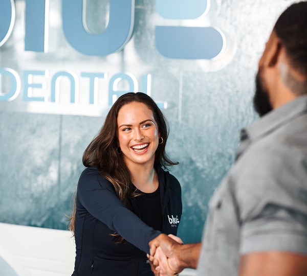 Get Immediate Relief: Expert Emergency Dentistry in Miami Shores. Dentist shaking hands with a joyful patient at Blu dental