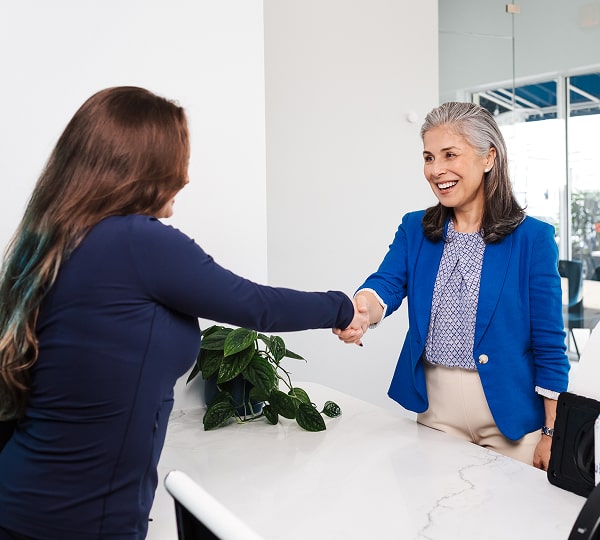 Regain Your Bite Strength with Dental Implants. Two women are shaking hands and smiling