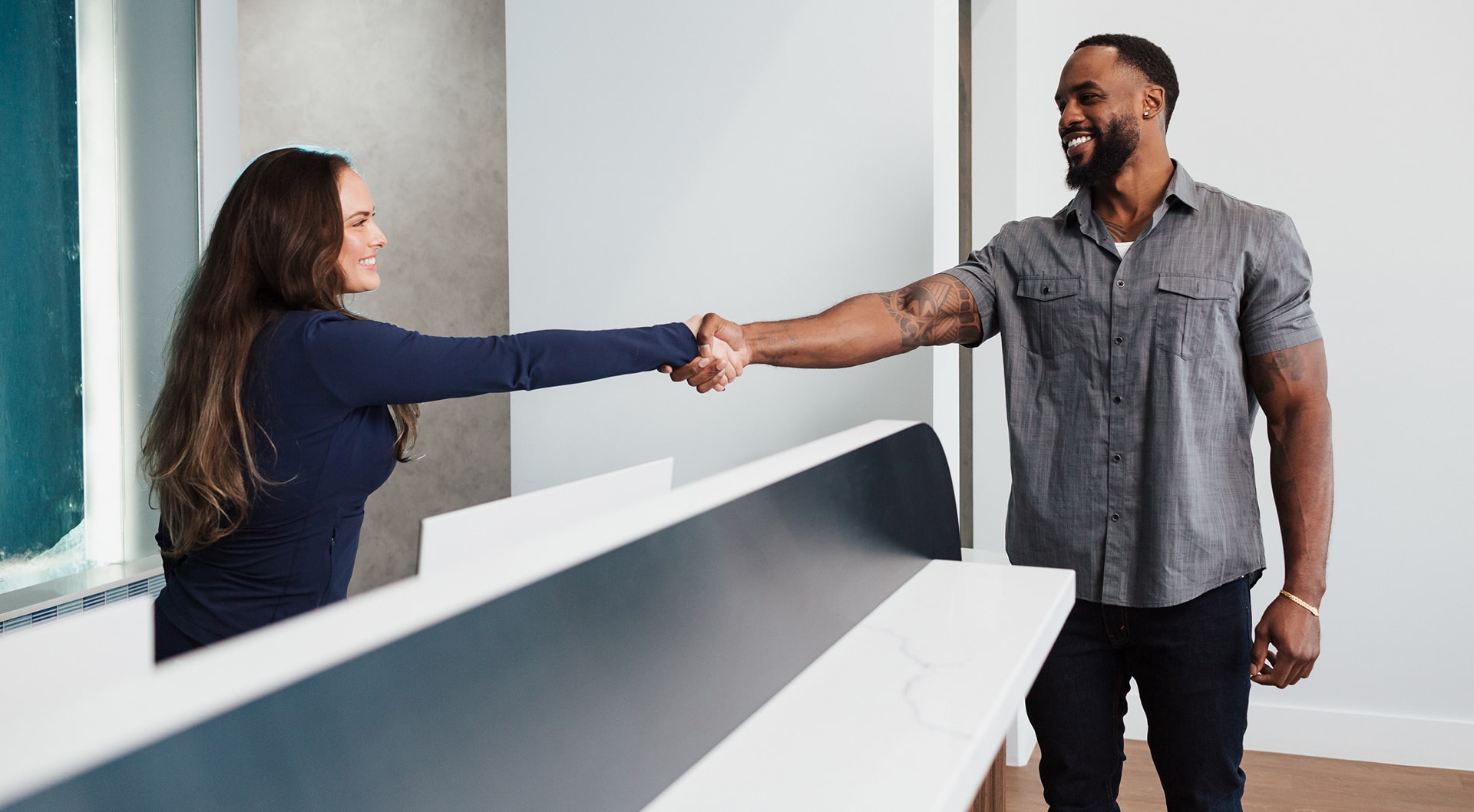 A man is shaking hands with Blu Dental front desk and smiling