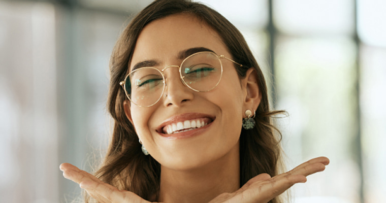 A woman in glasses smiling happily
