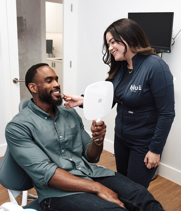 Save Your Tooth with Gentle, Pain-Free Root Canal Therapy. Blu Dental Team member is smiling with a patient in a dental chair