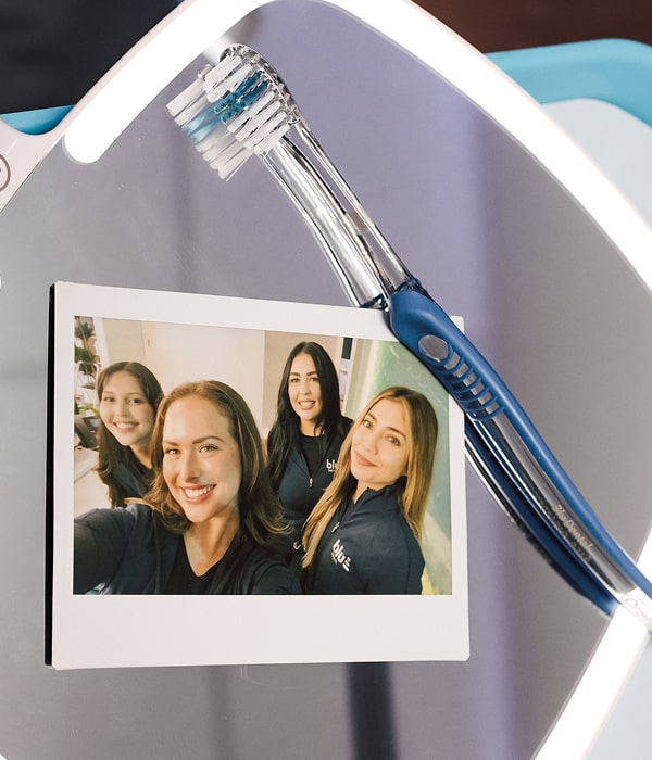Blu Dental team is smiling at polaroid near toothbrush on the table