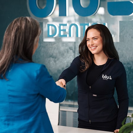 Blu Dental specialist shaking hands with a client and sliming