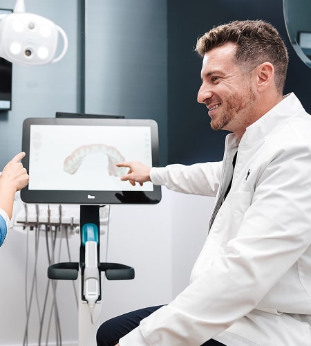 Dentist pointing to the digital model of a jaw and smiling