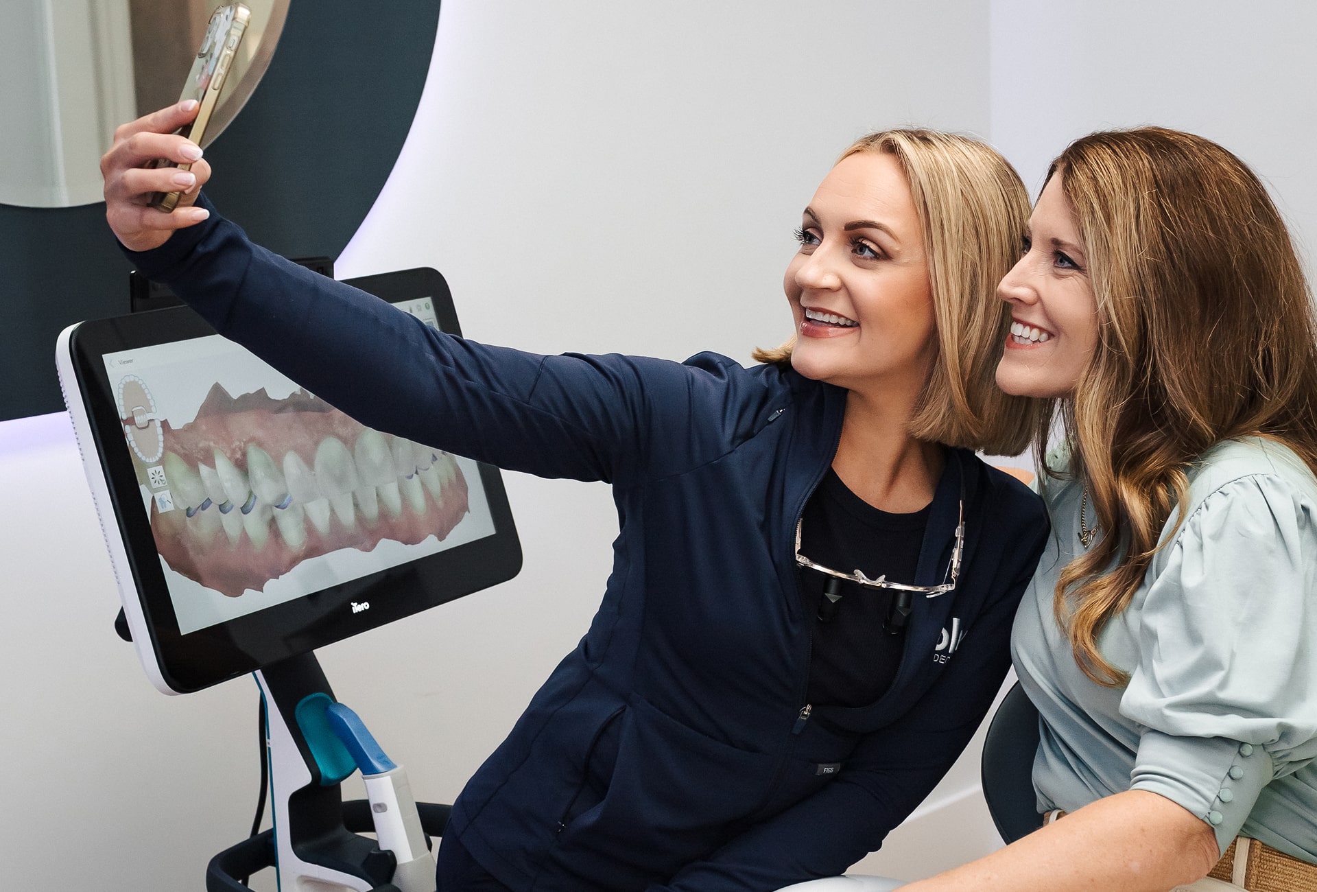 Dentist is making selfie with a joyful client in a dental chair