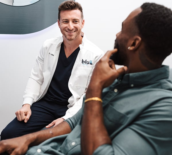 Safe, Comfortable Tooth Extractions by Blu Dental Experts. Dr. Jared is happily smiling with his patient in a dental chair