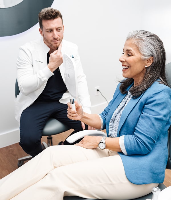 Restore Your Smile with Bone Grafting at Blu Dental. Top Blu Dental Dentist is smiling with a joyful patient in a chair