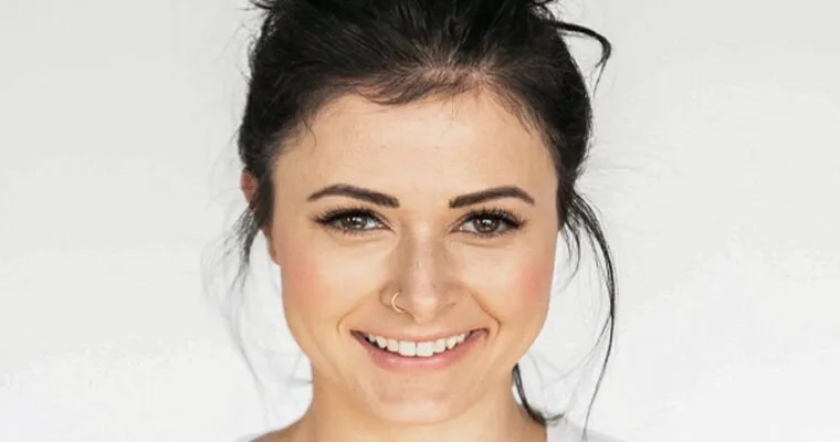 Woman with dark hair tied in a bun smiles