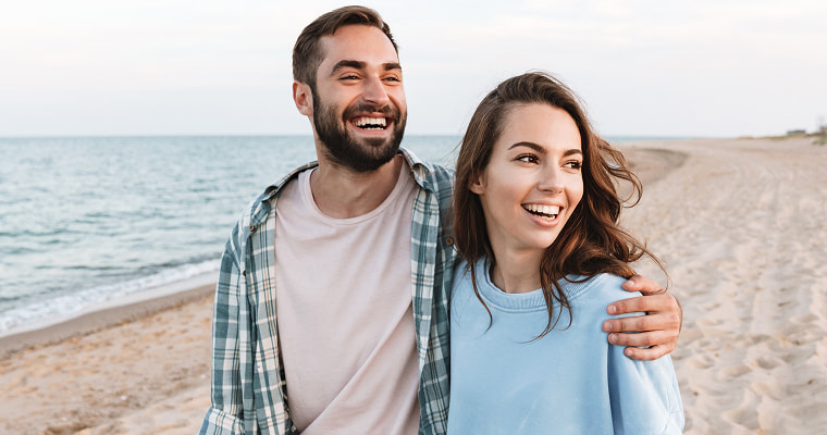 A young couple smiling on a beach
