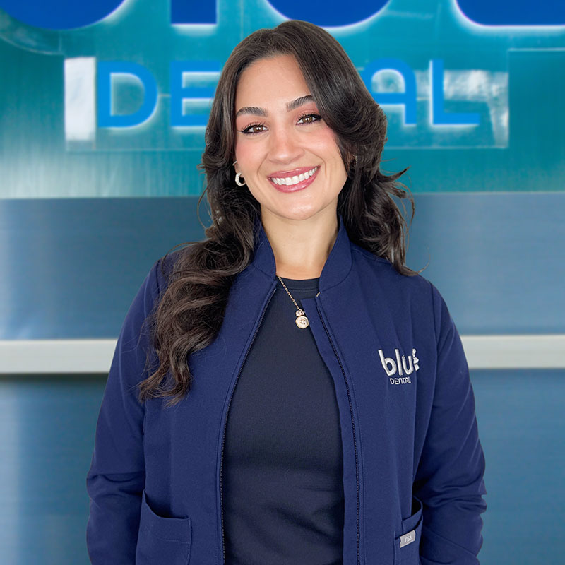 Dr. Chloe standing in front of the Blu Dental Sign