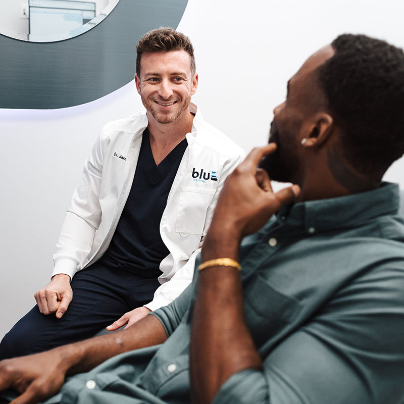 Dr. Jared sitting with his patient while smiling