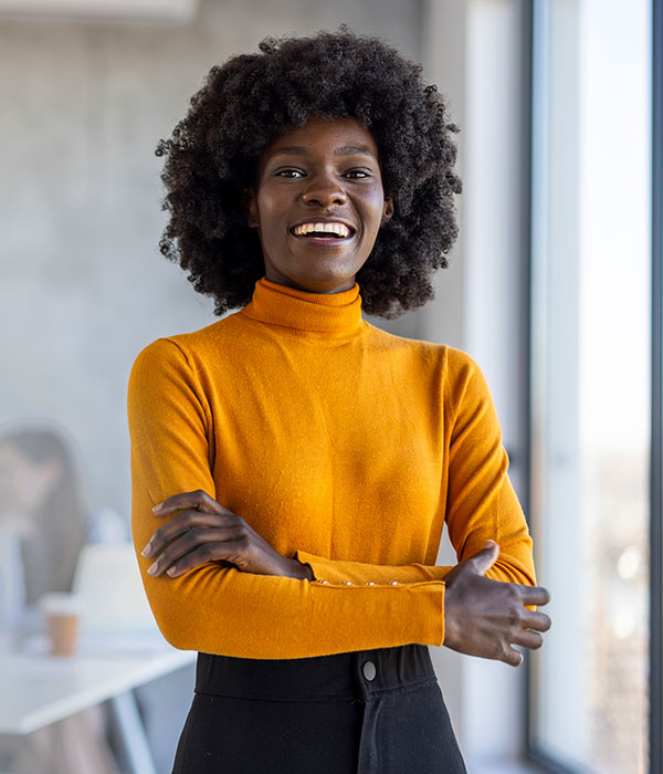 A woman smiling in an office wearing a yellow shirt